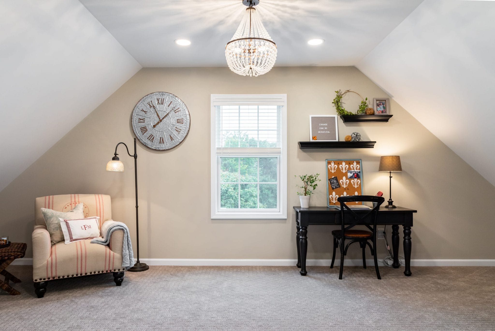 Remodeled bonus room in a finished attic space with light beige carpet, a small desk and chair, and a double-hung window in a beige wall.