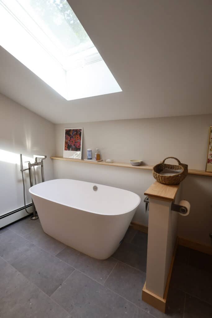 Bathroom renovation featuring freestanding soaking tub, skylight, and modern minimalist design