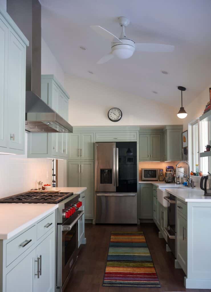 Completed kitchen renovation featuring modern cabinetry, gas range, white countertops, and updated lighting